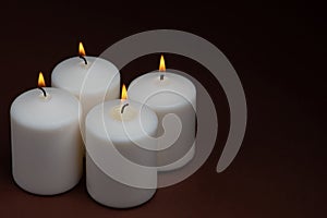 Four whiteÃÂ candlesÃÂ flameÃÂ burningÃÂ onÃÂ dark backgroundÃÂ withÃÂ copyÃÂ space forÃÂ text photo